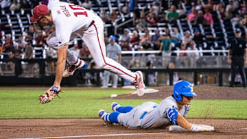 Jun 17, 2025; Omaha, Neb, USA; UCLA Bruins first baseman Mulivai Levu (39) slides to third after hitting a triple against Arkansas Razorbacks third baseman Brent Iredale (10) during the ninth inning at Charles Schwab Field. Mandatory Credit: Dylan Widger-Imagn Images