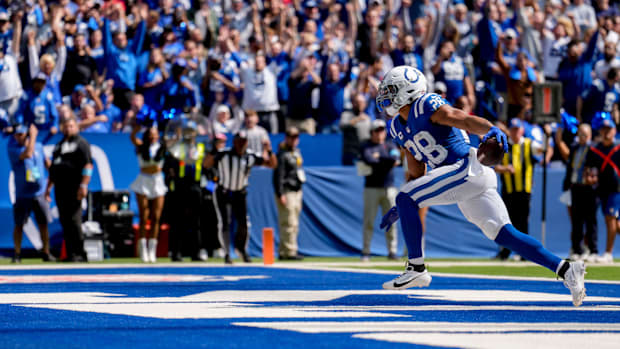 Colts running back Jonathan Taylor (blue jersey; white helmet) runs in a touchdown in front of a screaming home crowd. 