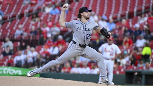 Dollander getting ready to release a white baseball in a grey uniform and black hat out of a black glov