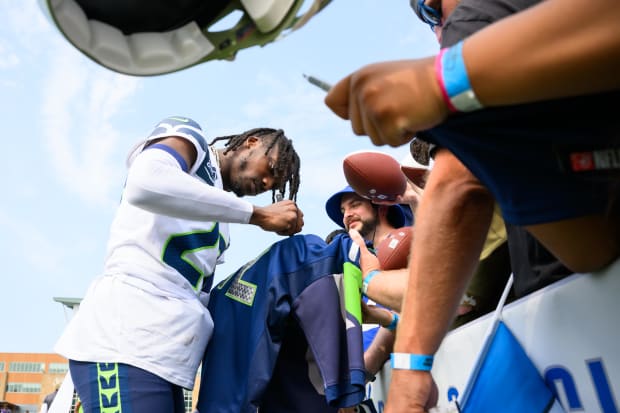 Seattle Seahawks cornerback Riq Woolen (27) signs autographs after training camp.