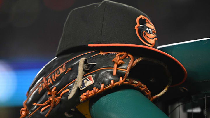 A Baltimore Orioles hat and glove rest on the dugout rail A Baltimore Orioles hat and glove rest on the dugout rail