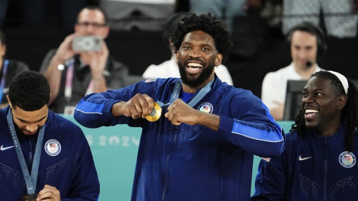 Aug 10, 2024; Paris, France; United States centre Joel Embiid (11) celebrates with the gold medal on the podium after defeating France in the men's basketball gold medal game during the Paris 2024 Olympic Summer Games at Accor Arena. Mandatory Credit: Rob Schumacher-USA TODAY Sports