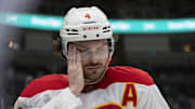 Apr 7, 2025; San Jose, California, USA;  Calgary Flames defenseman Rasmus Andersson (4) wipes the inside of his visor during the second period against the San Jose Sharks at SAP Center at San Jose. Mandatory Credit: Stan Szeto-Imagn Images