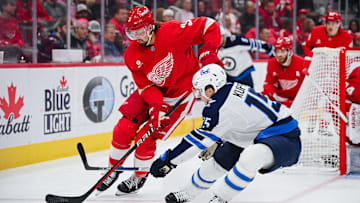 Oct 30, 2024; Detroit, Michigan, USA; Detroit Red Wings defenseman Justin Holl (3) and Winnipeg Jets center Rasmus Kupari (15) battle for the puck during the game at Little Caesars Arena. Mandatory Credit: Tim Fuller-Imagn Images