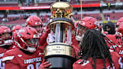 Nov 29, 2025; Louisville, Kentucky, USA;  Louisville Cardinals celebrate with the Governor’s Cup after defeating the Kentucky Wildcats at L&N Federal Credit Union Stadium. Louisville defeated Kentucky 41-0. Mandatory Credit: Jamie Rhodes-Imagn Images