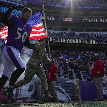 Nov 12, 2023; Baltimore, Maryland, USA;  Baltimore Ravens linebacker Kyle Van Noy (50) takes the field with a military service member before a game against the Cleveland Browns at M&T Bank Stadium. Mandatory Credit: Jessica Rapfogel-Imagn Images