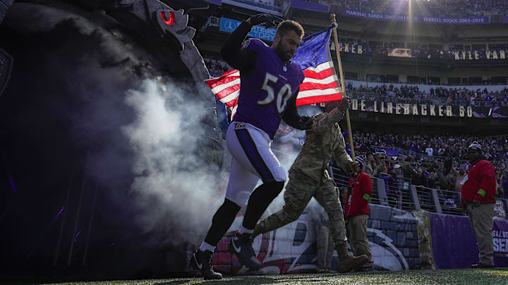 Nov 12, 2023; Baltimore, Maryland, USA;  Baltimore Ravens linebacker Kyle Van Noy (50) takes the field with a military service member before a game against the Cleveland Browns at M&T Bank Stadium. Mandatory Credit: Jessica Rapfogel-Imagn Images