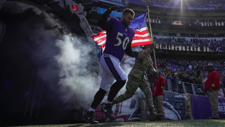 Nov 12, 2023; Baltimore, Maryland, USA;  Baltimore Ravens linebacker Kyle Van Noy (50) takes the field with a military service member before a game against the Cleveland Browns at M&T Bank Stadium. Mandatory Credit: Jessica Rapfogel-USA TODAY Sports