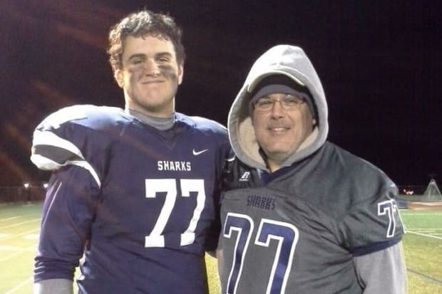 Football player Matt Goncalves stands next to his father in a navy jersey.