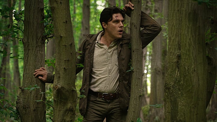 Finn Wittrock as Richard standing in the forest between trees