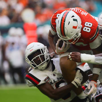 Sep 14, 2024; Miami Gardens, Florida, USA; Miami Hurricanes tight end Riley Williams (88) runs with the football against Ball State Cardinals linebackers Keionte Newson (9) and Caden Johnson (6) during the first quarter at Hard Rock Stadium. Mandatory Credit: Sam Navarro-Imagn Images