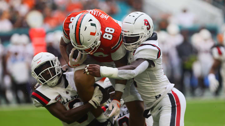 Sep 14, 2024; Miami Gardens, Florida, USA; Miami Hurricanes tight end Riley Williams (88) runs with the football against Ball State Cardinals linebackers Keionte Newson (9) and Caden Johnson (6) during the first quarter at Hard Rock Stadium. Mandatory Credit: Sam Navarro-Imagn Images