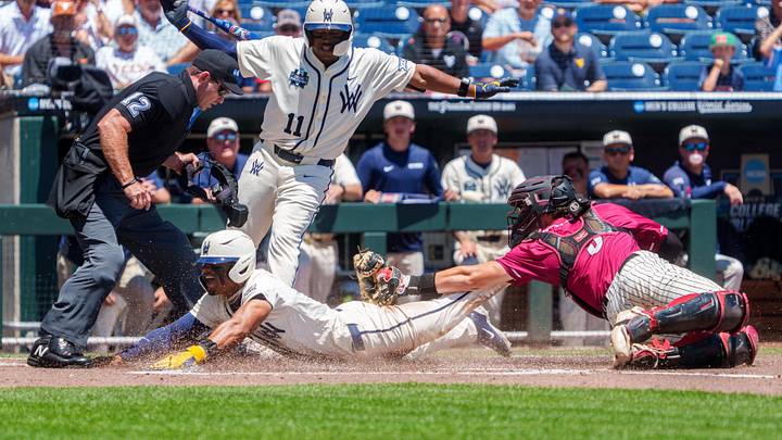 Jun 12, 2026; Omaha, NE, USA; West Virginia Mountaineers right fielder Armani Guzman (5) steals home to score against Troy Trojans catcher Jimmy Janicki (5) during the first inning at Charles Schwab Field. Mandatory Credit: Dylan Widger-Imagn Images