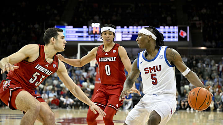 Feb 17, 2026; Dallas, Texas, USA; SMU Mustangs guard Jaron Pierre Jr. (5) looks to move the ball past Louisville Cardinals forward Vangelis Zougris (53) and guard Mikel Brown Jr. (0) during the second half at Moody Coliseum. Mandatory Credit: Jerome Miron-Imagn Images