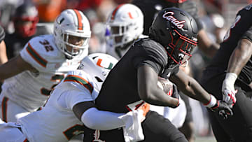 Oct 19, 2024; Louisville, Kentucky, USA;  Louisville Cardinals running back Donald Chaney (21) runs the ball against Miami Hurricanes linebacker Jaylin Alderman (21) during the second half at L&N Federal Credit Union Stadium. Miami defeated Louisville 52-45. Mandatory Credit: Jamie Rhodes-Imagn Images