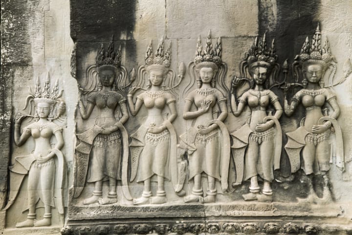 A group of asparas carved into a wall in Angkor Wat.