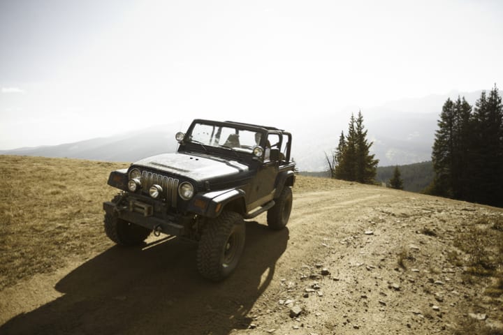 A four-wheel drive Jeep on a mountain summit.