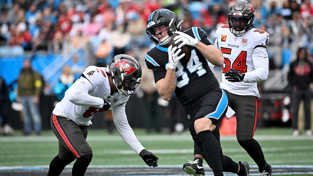 Dec 21, 2025; Charlotte, North Carolina, USA; Carolina Panthers tight end Mitchell Evans (84) runs against Tampa Bay Buccaneers linebacker Sirvocea Dennis (8) and linebacker Lavonte David (54) during the first half at Bank of America Stadium. Mandatory Credit: Bob Donnan-Imagn Images