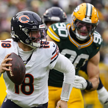 Jan 5, 2025; Green Bay, Wisconsin, USA;  Chicago Bears quarterback Caleb Williams (18) scrambles away from pressure applied by Green Bay Packers defensive lineman Lukas Van Ness (90) during the first quarter at Lambeau Field. Mandatory Credit: Jeff Hanisch-Imagn Images