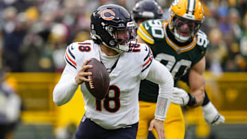 Jan 5, 2025; Green Bay, Wisconsin, USA;  Chicago Bears quarterback Caleb Williams (18) scrambles away from pressure applied by Green Bay Packers defensive lineman Lukas Van Ness (90) during the first quarter at Lambeau Field. Mandatory Credit: Jeff Hanisch-Imagn Images