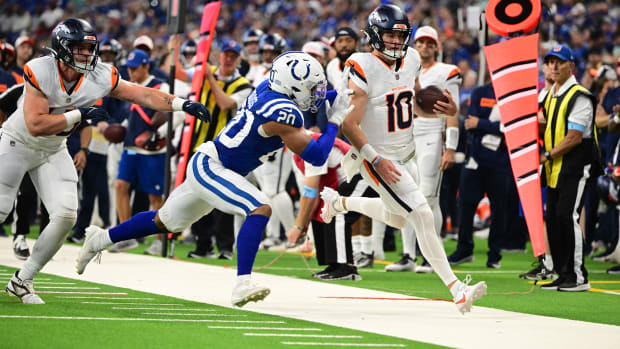 Colts safety Nick Cross (blue jersey with white pants/helmet) tackles the opposing quarterback (all-white uniform). 