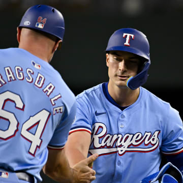 Apr 7, 2024; Arlington, Texas, USA; Texas Rangers first base coach Corey Ragsdale (64) congratulates Rangers pinch hitter Justin Foscue (56) after Ragsdale gets his first career MLB hit and run batted in during the ninth inning against the Houston Astros at Globe Life Field.