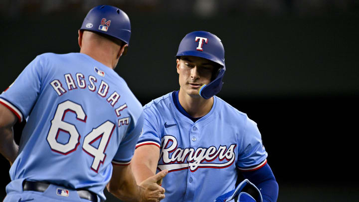 Apr 7, 2024; Arlington, Texas, USA; Texas Rangers first base coach Corey Ragsdale (64) congratulates Rangers pinch hitter Justin Foscue (56) after Ragsdale gets his first career MLB hit and run batted in during the ninth inning against the Houston Astros at Globe Life Field.