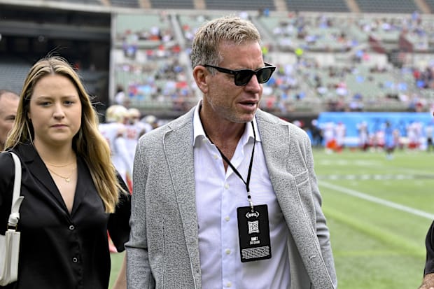 Former NFL player Troy Aikman walks on the field before the game 