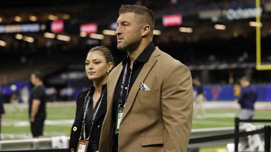 Tim Tebow (left) and wife Demi-Leigh Tebow (right) walk on the field prior to the game between the Notre Dame Fighting Irish and the Georgia Bulldogs at Caesars Superdome.