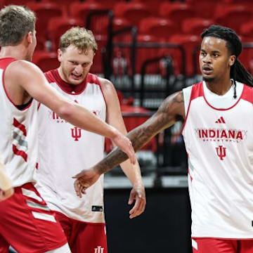 Indiana basketball guard Lamar Wilkerson high-fives teammate Trent Sisley, standing between Tucker DeVries and Ian Stephens.