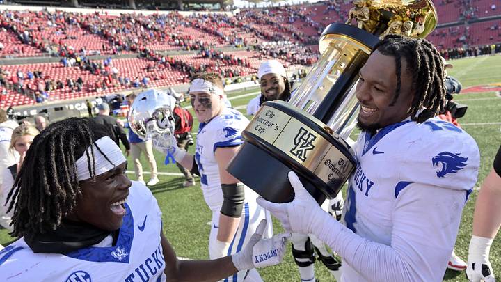 Nov 25, 2023; Louisville, Kentucky, USA;  Louisville Cardinals defensive back Gilbert Frierson (13) and defensive back Maxwell Hairston (31) celebrated with the Governor   s Cup following the second half against the Louisville Cardinals at L&N Federal Credit Union Stadium. Kentucky defeated Louisville 38-31. Mandatory Credit: Jamie Rhodes-Imagn Images
