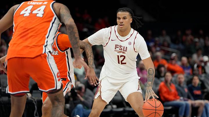 Mar 11, 2025; Charlotte, NC, USA; Florida State Seminoles forward Malique Ewin (12) with the ball as Syracuse Orange center Eddie Lampkin Jr. (44) defends in the first half at Spectrum Center. Mandatory Credit: Bob Donnan-Imagn Images