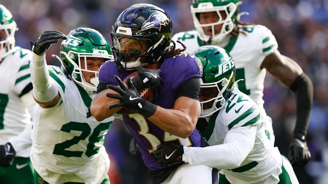 Nov 23, 2025; Baltimore, Maryland, USA;  Baltimore Ravens running back Keaton Mitchell (34) rushes as New York Jets safety Isaiah Oliver (26) and New York Jets safety Tony Adams (22) defend during the second quarter at M&T Bank Stadium. Mandatory Credit: Peter Casey-Imagn Images