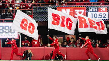 Nov 23, 2024; Lincoln, Nebraska, USA; Nebraska Cornhuskers cheerleaders carry flags across the field after a score against the Wisconsin Badgers during the fourth quarter at Memorial Stadium. Mandatory Credit: Dylan Widger-Imagn Images