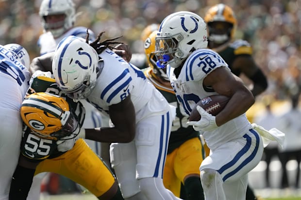 Indianapolis Colts half back Jonathan Taylor runs with the football with a block from tight end Mo Alie-Cox in white jerseys.