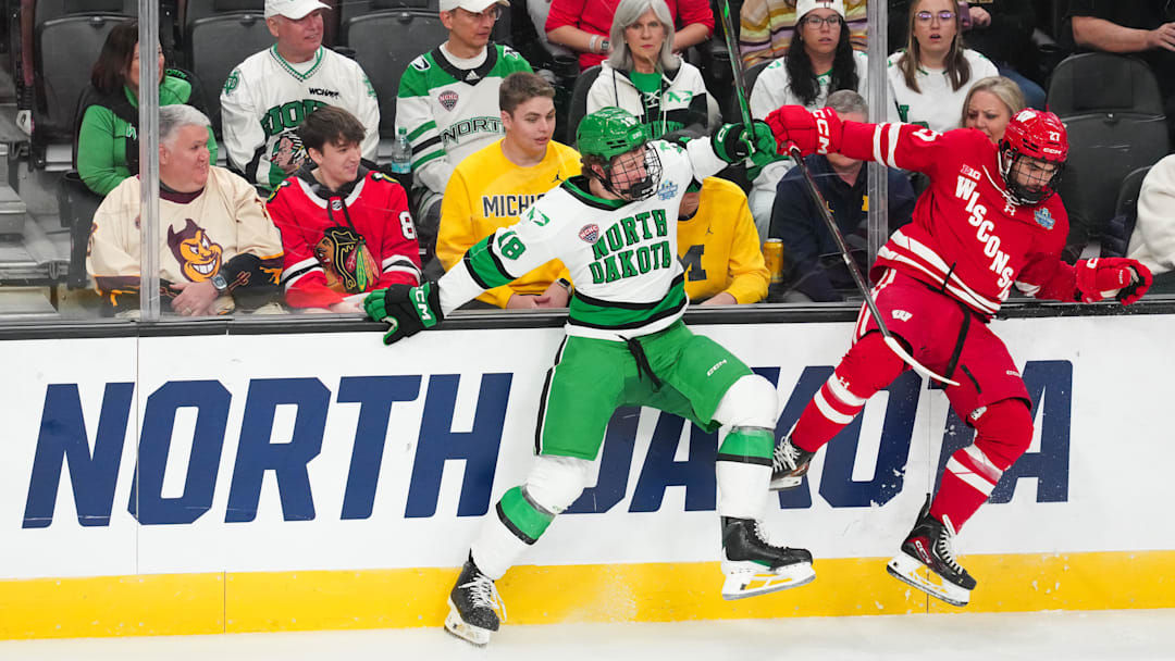 Apr 9, 2026; Las Vegas, Nevada, UNITED STATES; North Dakota Fighting Hawks defenseman Keaton Verhoeff (18) is checked by Wisconsin Badgers forward Finn Brink (27) in the first period in the semifinals of the NCAA men's ice hockey Frozen Four at T-Mobile Arena. Mandatory Credit: Stephen R. Sylvanie-Imagn Images