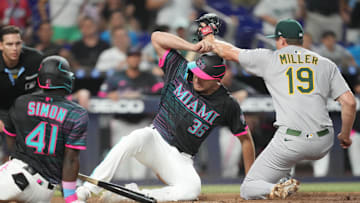 May 3, 2025; Miami, Florida, USA;  Miami Marlins designated hitter Matt Mervis (36) slides under the tag of Oakland Athletics pitcher Mason Miller (19) following a wild pitch during the at bat of left fielder Ronny Simon (41) in the ninth inning at loanDepot Park. 