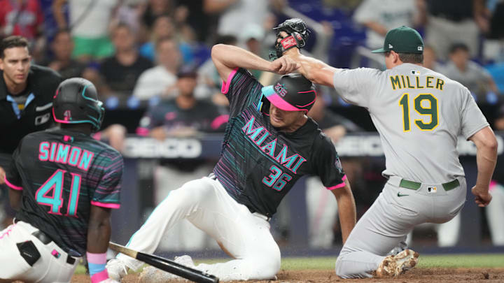 May 3, 2025; Miami, Florida, USA;  Miami Marlins designated hitter Matt Mervis (36) slides under the tag of Oakland Athletics pitcher Mason Miller (19) following a wild pitch during the at bat of left fielder Ronny Simon (41) in the ninth inning at loanDepot Park. 