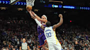 Nov 30, 2024; Phoenix, Arizona, USA; Phoenix Suns guard Devin Booker (1) puts up a layup over Golden State Warriors forward Jonathan Kuminga (00) during the second half at Footprint Center. Mandatory Credit: Joe Camporeale-Imagn Images