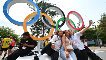 Olympic fans take selfies in front of the iconic rings in Paris.