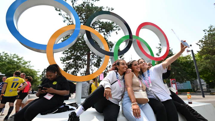 Olympic fans take selfies in front of the iconic rings in Paris.