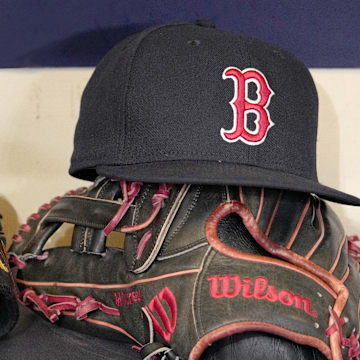 May 27, 2025; Milwaukee, Wisconsin, USA; A Boston Red Sox hat and glove sit in the dug out before a game against the Milwaukee Brewers at American Family Field. Mandatory Credit: Michael McLoone-Imagn Images