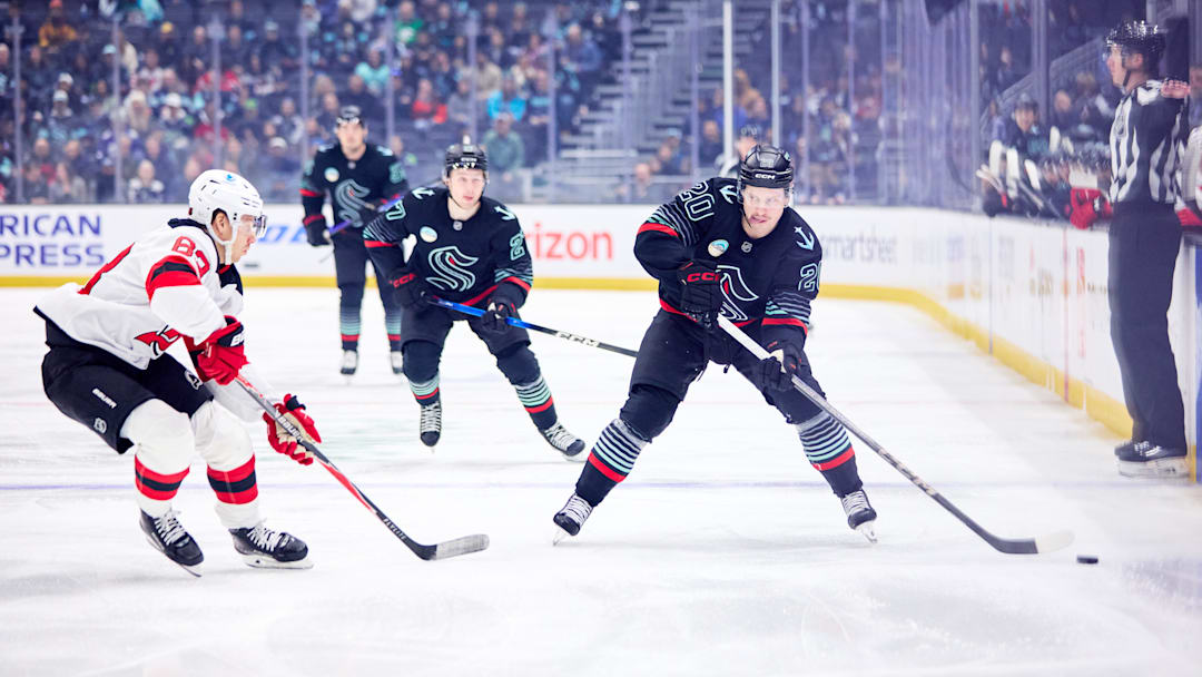 Jan 25, 2026; Seattle, Washington, USA; Seattle Kraken right wing Eeli Tolvanen (20) looks to pass as New Jersey Devils center Juho Lammikko (83) defends during the first period at Climate Pledge Arena. Mandatory Credit: Blake Dahlin-Imagn Images
