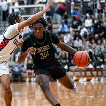 East Lansing's Brian Windham Jr., left, guards Ann Arbor Huron's Macari Moore during the first quarter on Tuesday, March 12, 2024, at Holt High School.