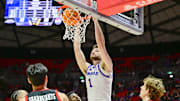 Feb 15, 2025; Salt Lake City, Utah, USA; Kansas Jayhawks center Hunter Dickinson (1) dunks over Utah Utes guard Mike Sharavjamts (25), and forward Zach Keller (32) during the first half at the Jon M. Huntsman Center. Mandatory Credit: Christopher Creveling-Imagn Images