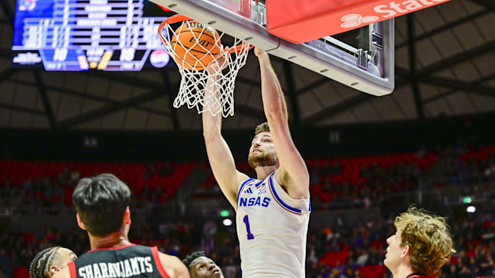 Feb 15, 2025; Salt Lake City, Utah, USA; Kansas Jayhawks center Hunter Dickinson (1) dunks over Utah Utes guard Mike Sharavjamts (25), and forward Zach Keller (32) during the first half at the Jon M. Huntsman Center. Mandatory Credit: Christopher Creveling-Imagn Images