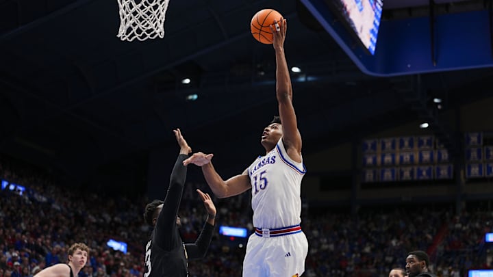 Dec 16, 2025; Lawrence, Kansas, USA; Kansas Jayhawks forward Bryson Tiller (15) shoots against Towson Tigers forward Caleb Embeya (23) during the second half at Allen Fieldhouse. Mandatory Credit: Jay Biggerstaff-Imagn Images