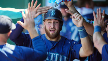 Jun 9, 2024; Kansas City, Missouri, USA; Seattle Mariners first baseman Tyler Locklear (27) is congratulated by teammates after scoring a run during the seventh inning against the Kansas City Royals at Kauffman Stadium. Mandatory Credit: Jay Biggerstaff-USA TODAY Sports