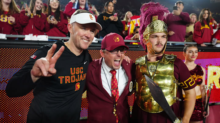 Nov 29, 2025; Los Angeles, California, USA; Southern California Trojans head coach Lincoln Riley (left) poses with Spirit of Troy marching band director James Vogel (center) and mascot Tommy Trojan after the game against the UCLA Bruins at United Airlines Field at Los Angeles Memorial Coliseum. Mandatory Credit: Kirby Lee-Imagn Images