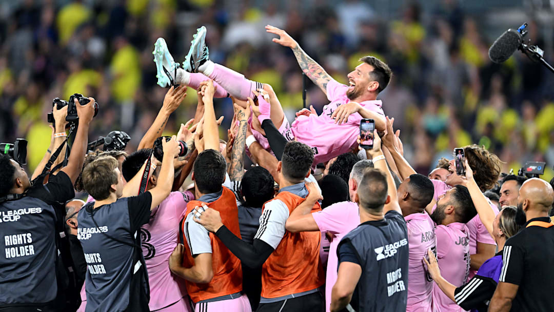 Inter Miami CF players toss a joyous Lionel Messi into the air while, in the background, yellow-clad Nashville SC fans head for the exits at Geodis Park after the Herons won a penalty-kick shootout to claim the 2023 Leagues Cup.